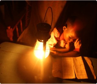 Uma criança a estudar com lâmpada de querosene